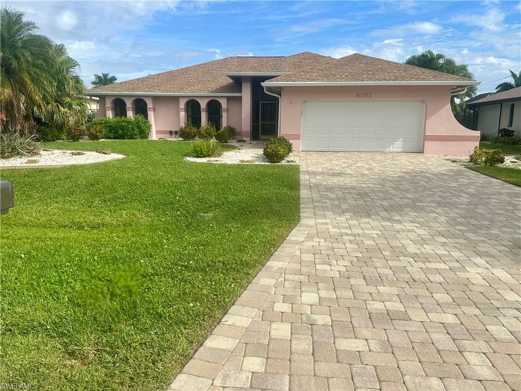 View of front of home featuring stucco siding, decorative driveway, a front yard, a garage, and roof with shingles