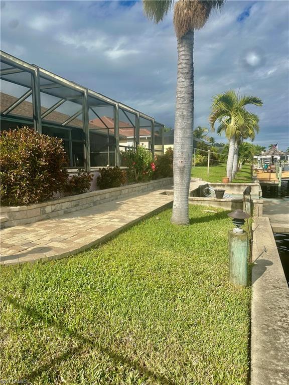 View of community with a yard, a patio area, and a sunroom