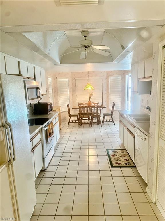 Kitchen featuring white cabinets, white appliances, light countertops, light tile patterned floors, and a ceiling fan