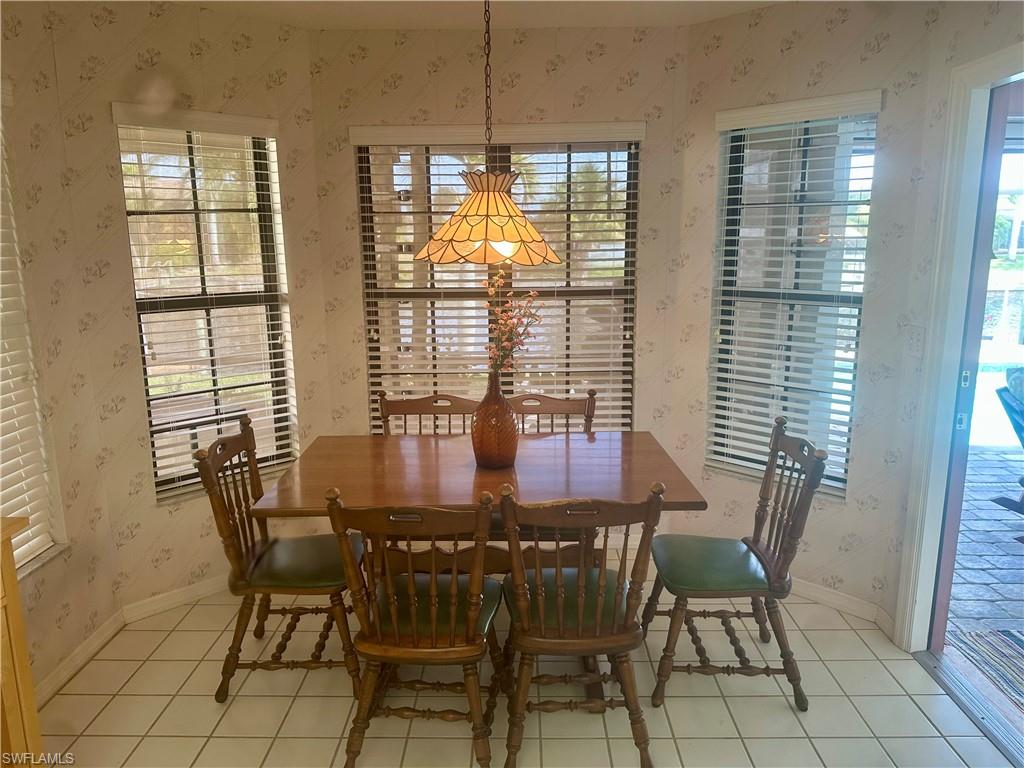 Dining area with wallpapered walls, healthy amount of natural light, and light tile patterned flooring
