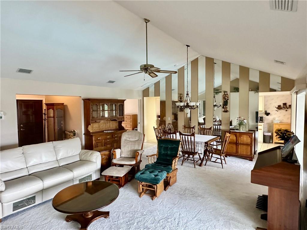 Living area featuring carpet, ceiling fan, and high vaulted ceiling