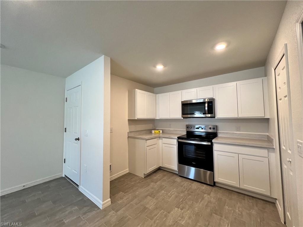Kitchen featuring stainless steel appliances, white cabinets, light countertops, wood tiled floors, and recessed lighting