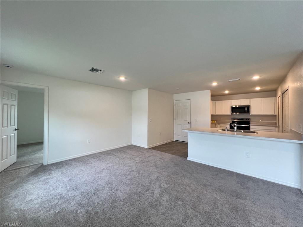 Unfurnished living room with recessed lighting and dark colored carpet