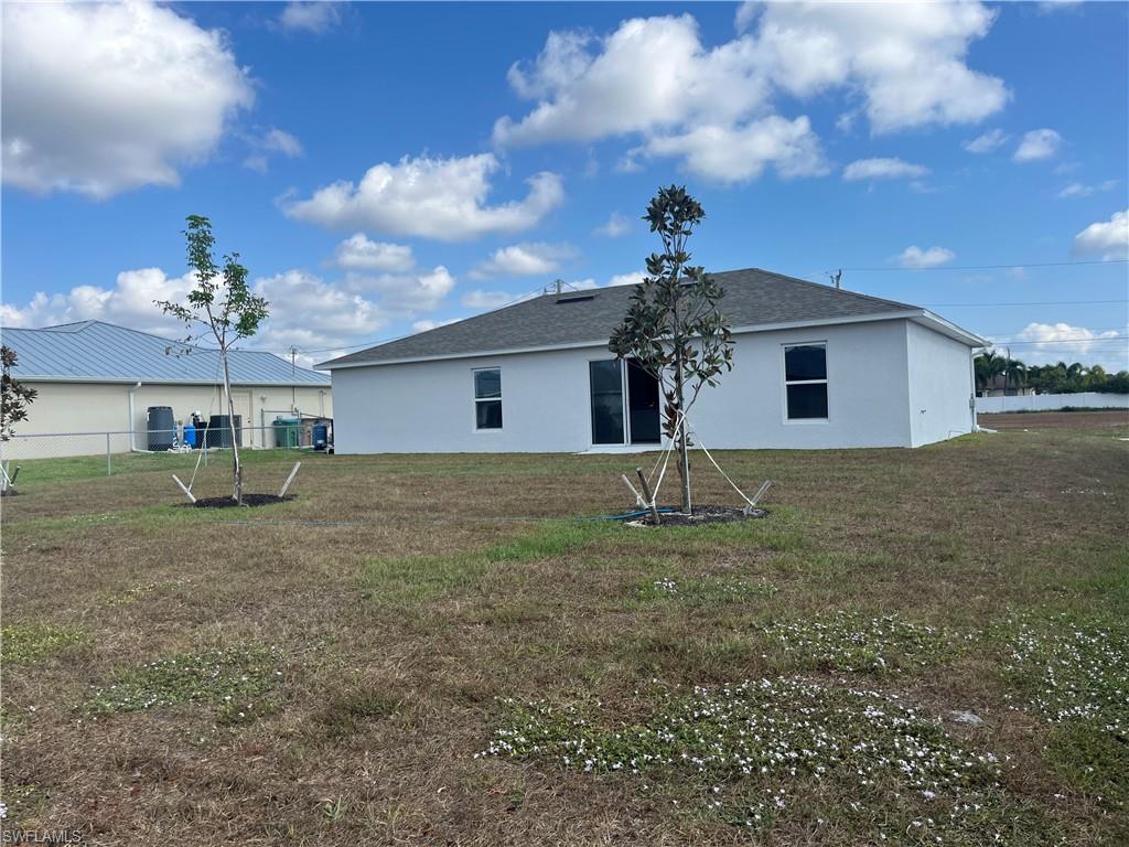 Back of property with stucco siding and a shingled roof