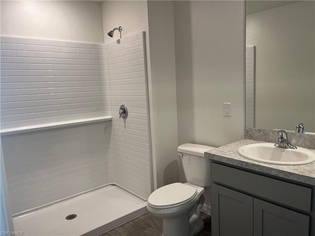 Full bathroom with vanity, a stall shower, and dark wood-style flooring