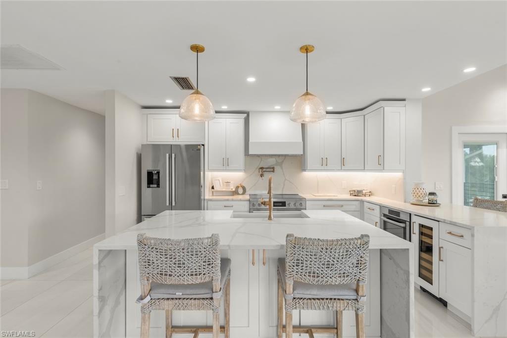 Kitchen with light stone counters, a kitchen breakfast bar, white cabinetry, a peninsula, and recessed lighting