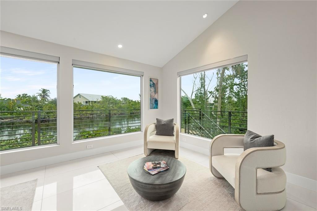 Living area featuring lofted ceiling, a water view, tile patterned floors, and recessed lighting