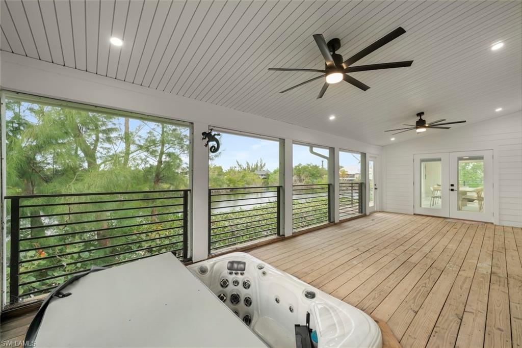 Sunroom with vaulted ceiling, french doors, ceiling fan, and a deck with water view