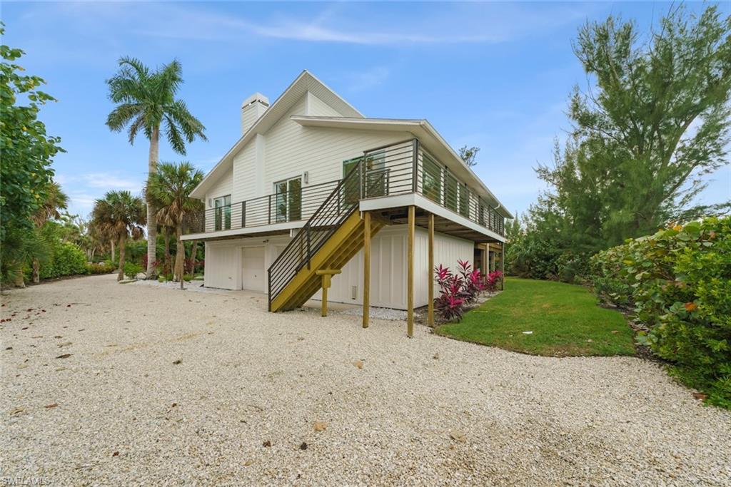 Rear view of house with a chimney, stairway, gravel driveway, a yard, and a deck