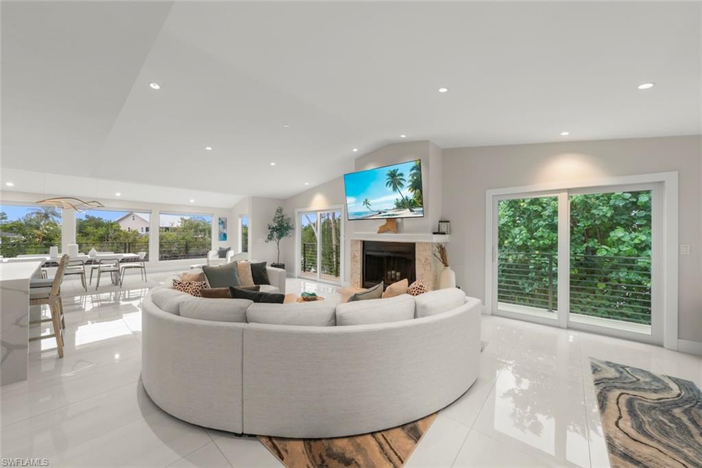 Living area featuring a premium fireplace, recessed lighting, lofted ceiling, light tile patterned floors, and plenty of natural light