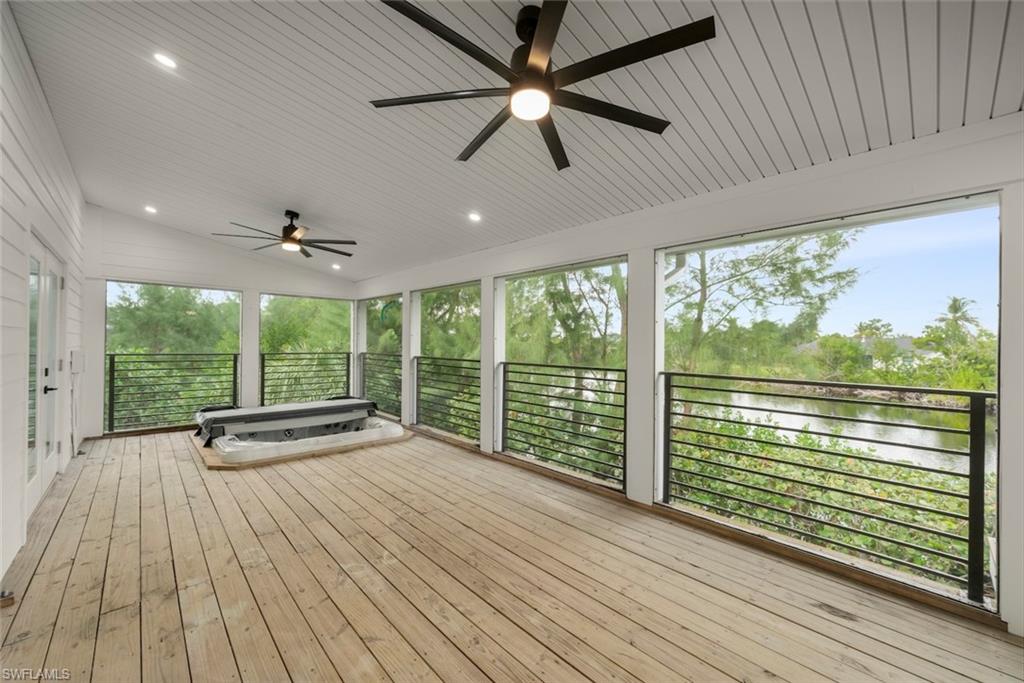 Wooden terrace with a ceiling fan, a water view, and a sunroom