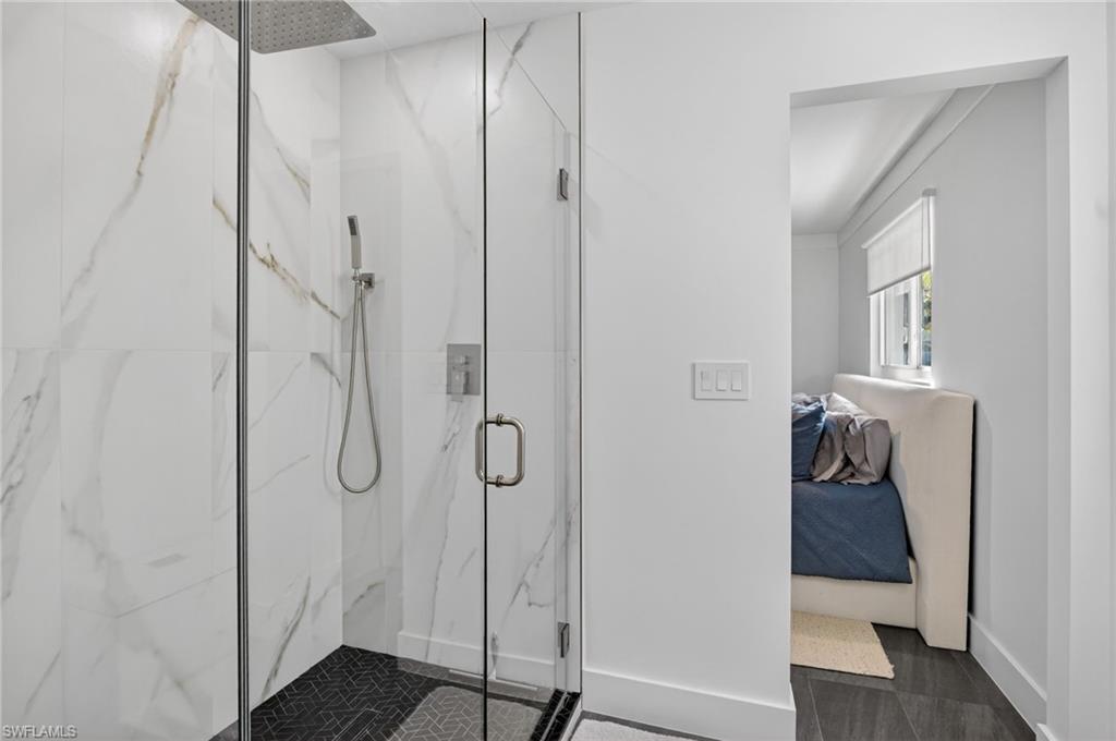Ensuite bathroom featuring a marble finish shower and baseboards