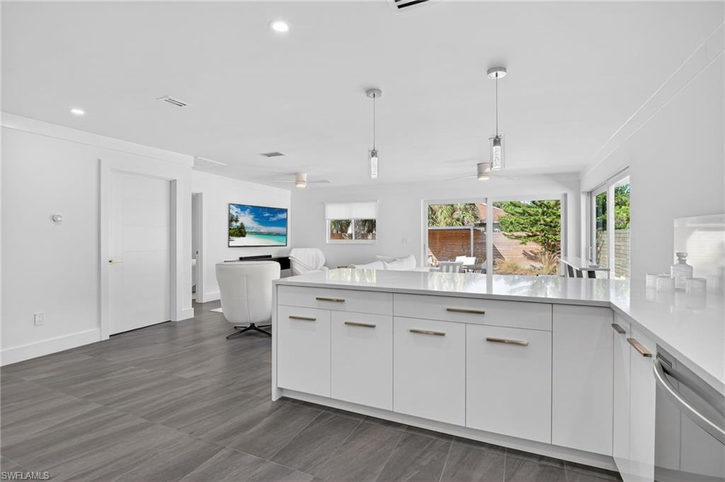 Kitchen with modern cabinets, decorative light fixtures, open floor plan, white cabinets, and recessed lighting