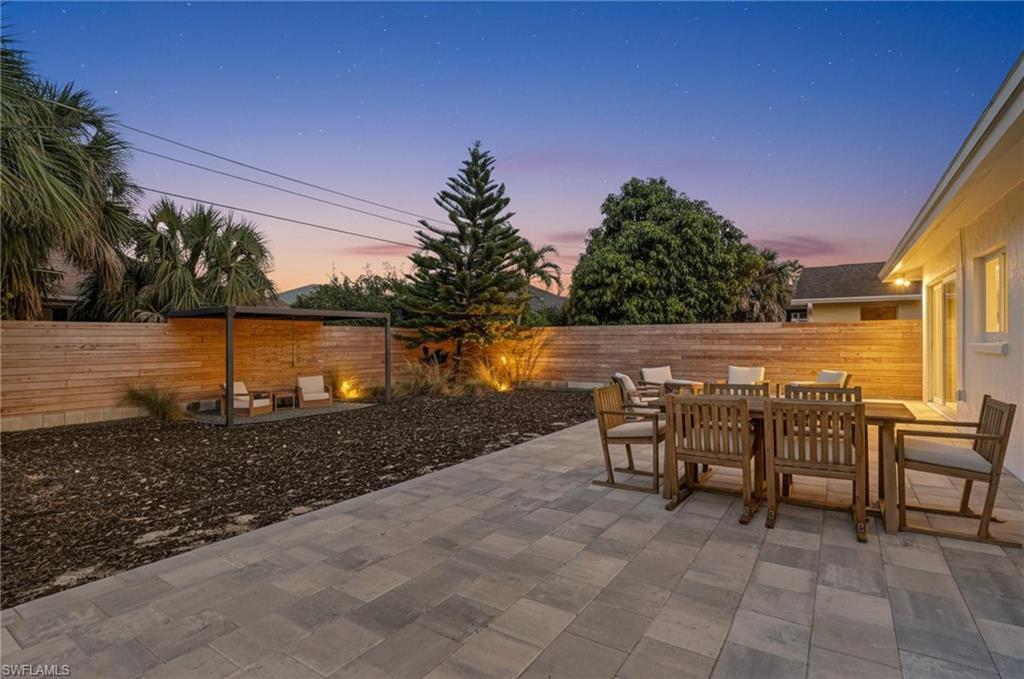 Patio terrace at dusk with outdoor dining area, a patio area, and a fenced backyard