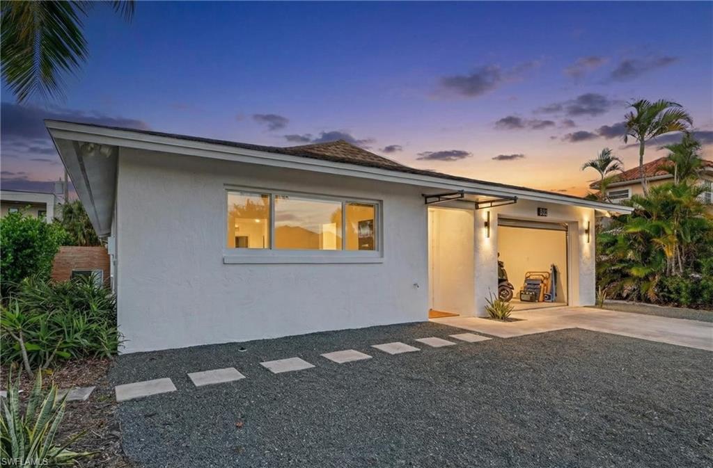 View of front of property featuring stucco siding, an attached garage, and driveway
