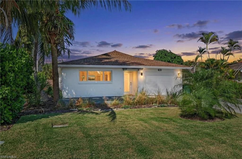 View of front of property with a front yard, stucco siding, and an attached garage