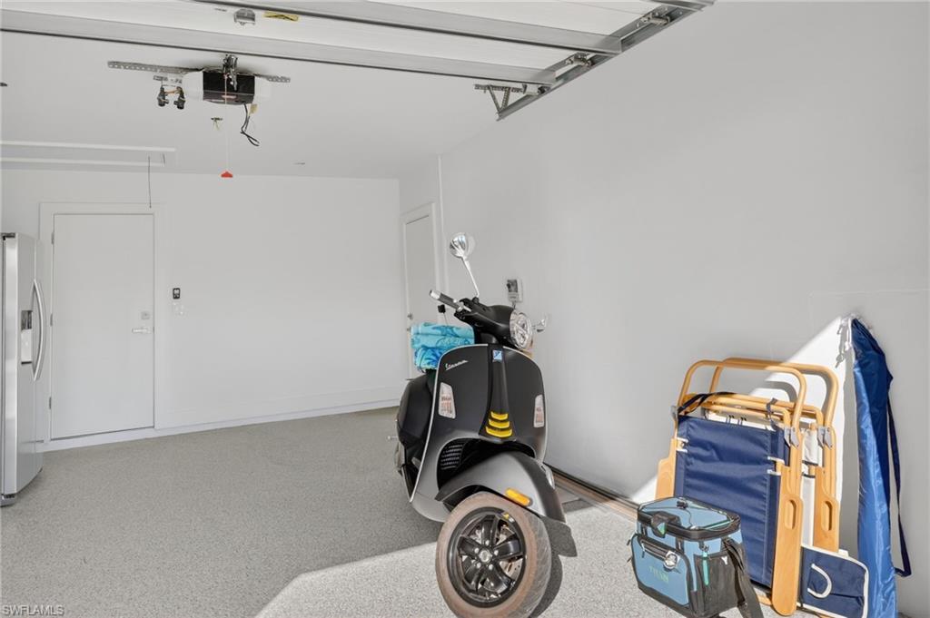 Garage with stainless steel fridge and a garage door opener