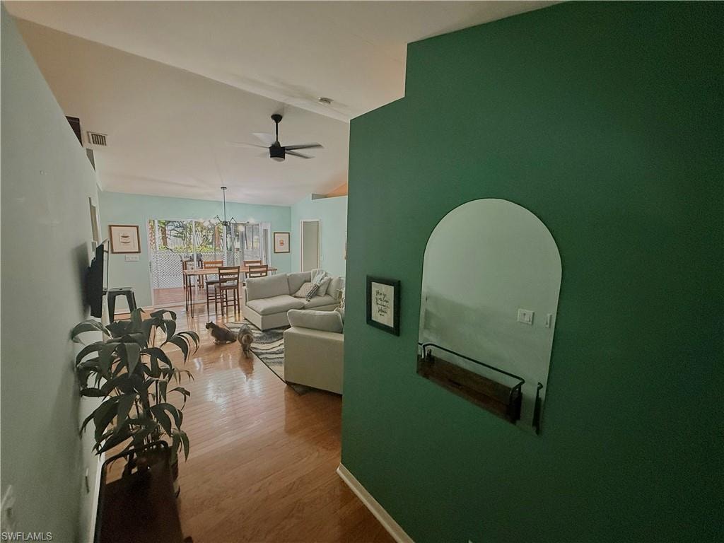 Hallway featuring vaulted ceiling and wood finished floors