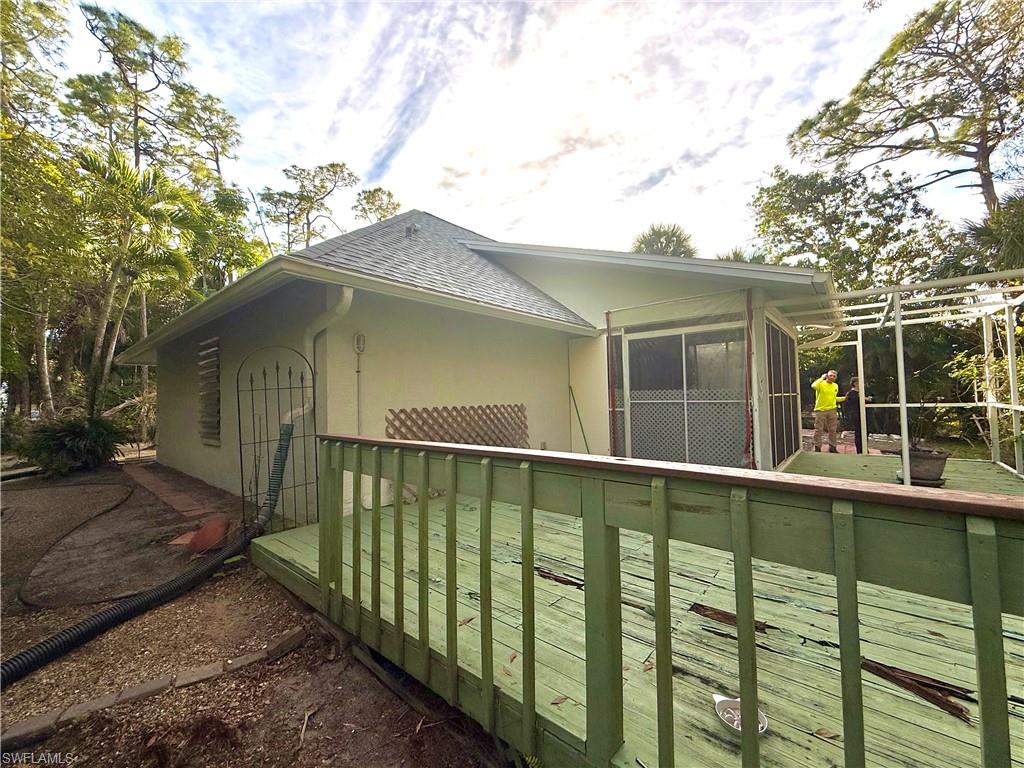 View of side of property with roof with shingles, stucco siding, and a sunroom