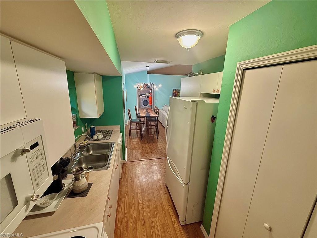 Laundry room with lofted ceiling, light wood-style floors, and a chandelier