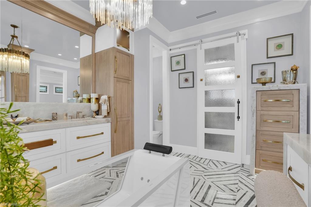 Bathroom featuring vanity, a chandelier, a whirlpool tub, crown molding, and recessed lighting - Virtually Edited Image
