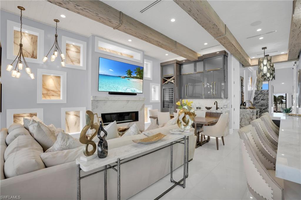 Living area with a chandelier, a high end fireplace, beamed ceiling, and recessed lighting - Virtually Edited Image