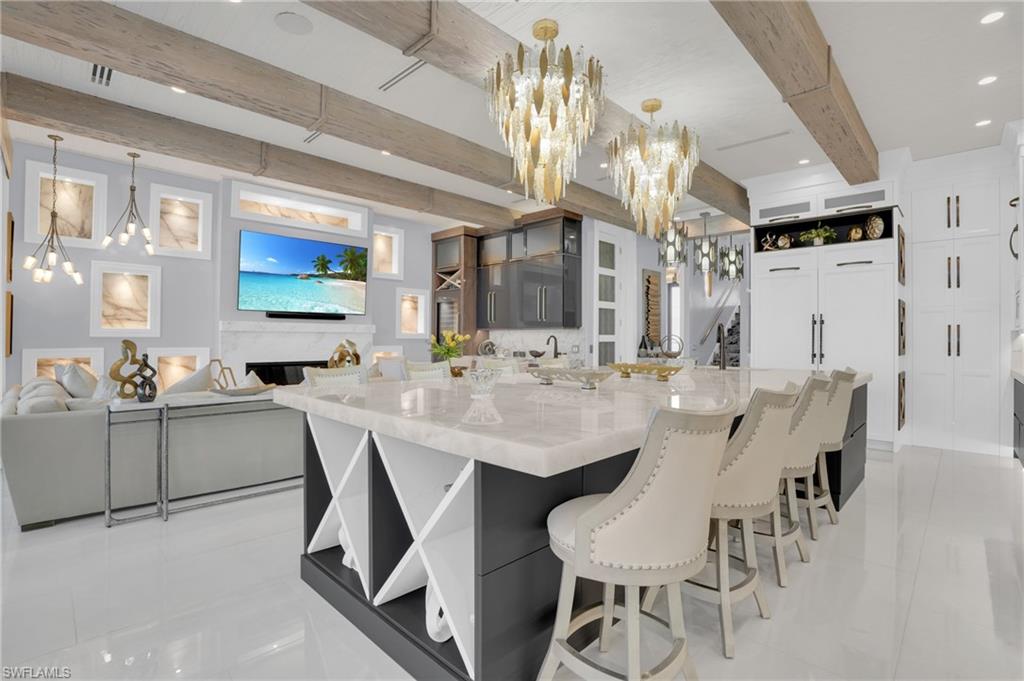 Kitchen featuring open shelves, a chandelier, white cabinets, a breakfast bar, and beam ceiling - Virtually Edited Image