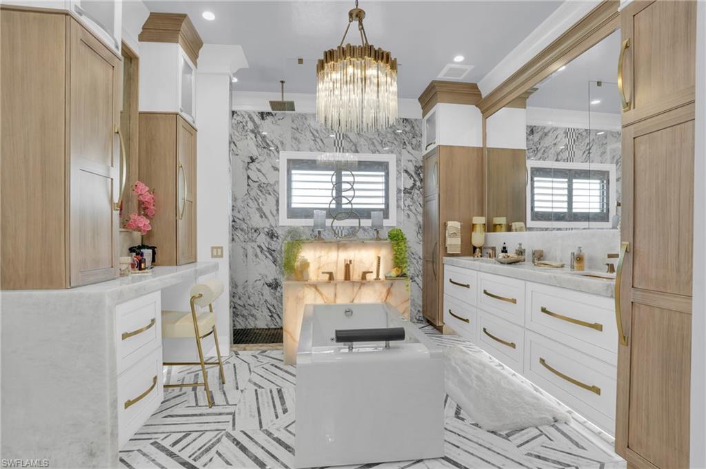 Bathroom with vanity, a marble finish shower, crown molding, a chandelier, and tile walls - Virtually Edited Image