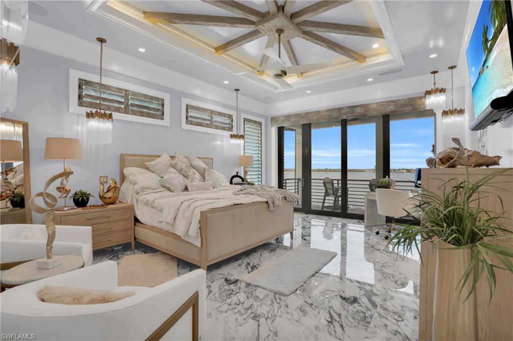 Bedroom with marble tiled flooring, access to outside, a chandelier, ceiling fan, and coffered ceiling - Virtually Edited Image