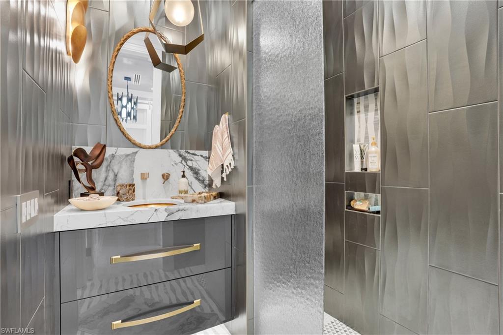 Full bathroom featuring vanity, tile walls, and walk in shower - Virtually Edited Image