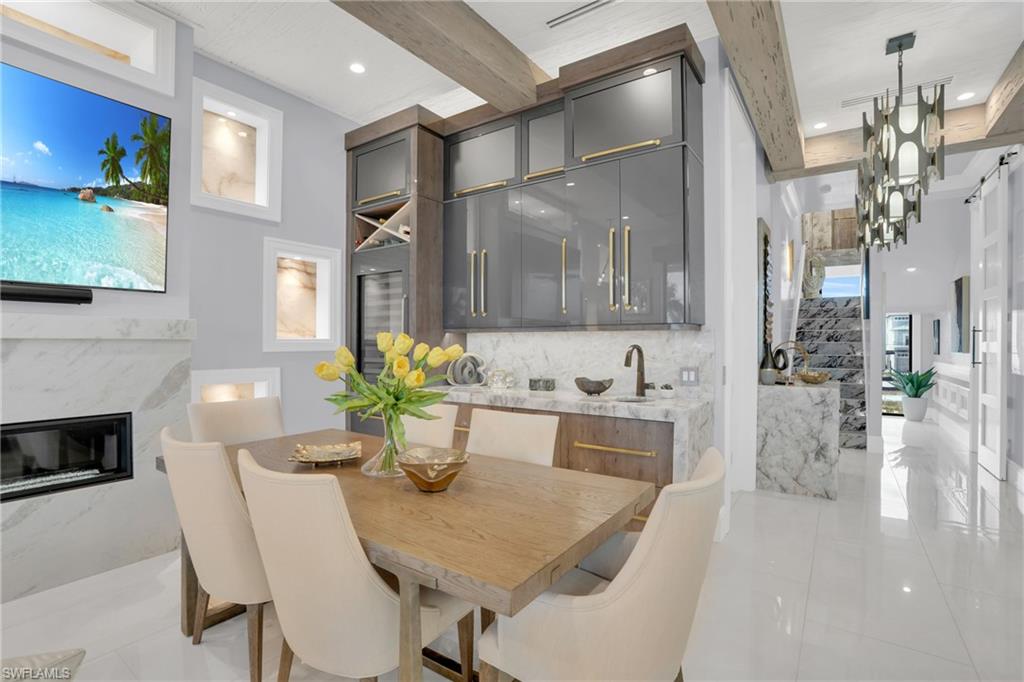 Dining space featuring beam ceiling, a fireplace, recessed lighting, and beverage cooler - Virtually Edited Image