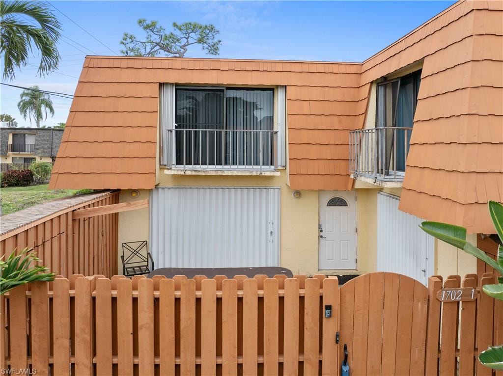 View of property exterior with a gate, mansard roof, and a balcony