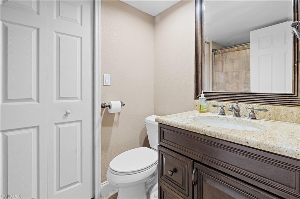 Full bath with a textured wall, vanity, a shower with curtain, and a closet