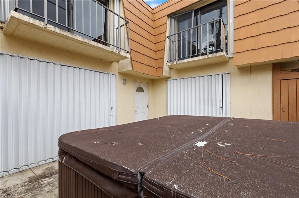 Doorway to property with stucco siding, a hot tub, and mansard roof