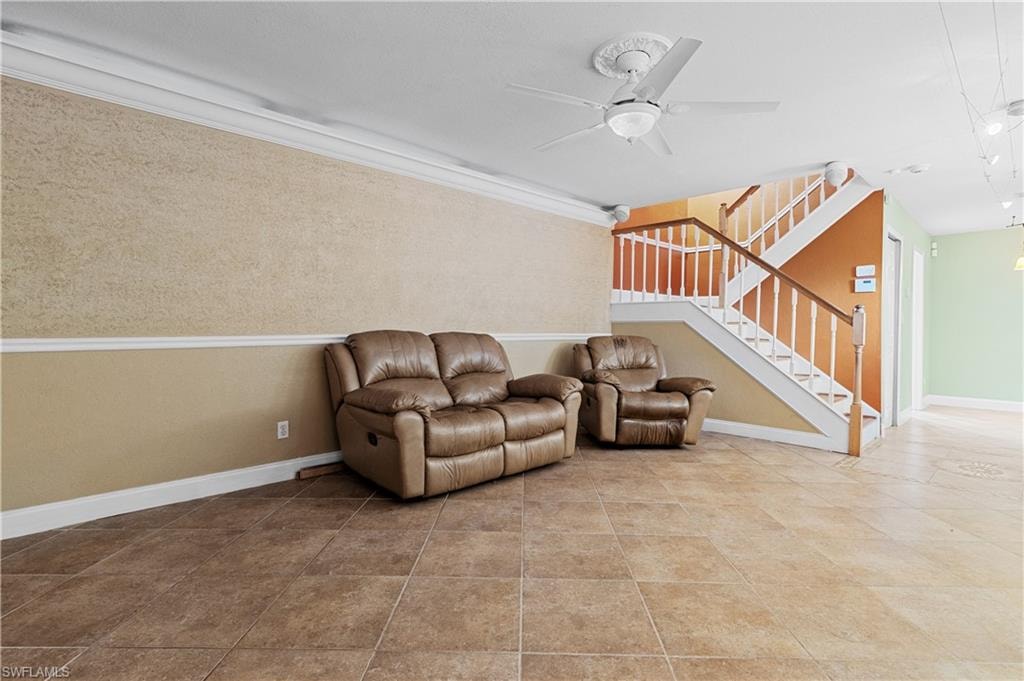 Living area featuring ceiling fan, stairs, and crown molding