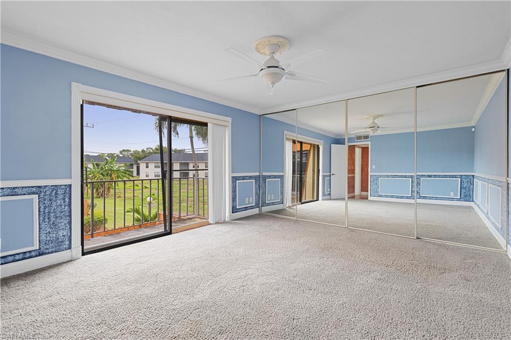 Unfurnished room featuring wainscoting, crown molding, a decorative wall, a ceiling fan, and carpet floors