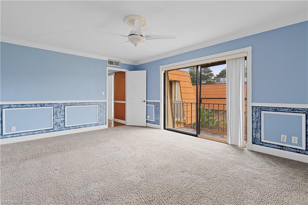 Carpeted spare room with a wainscoted wall, crown molding, ceiling fan, and wallpapered walls