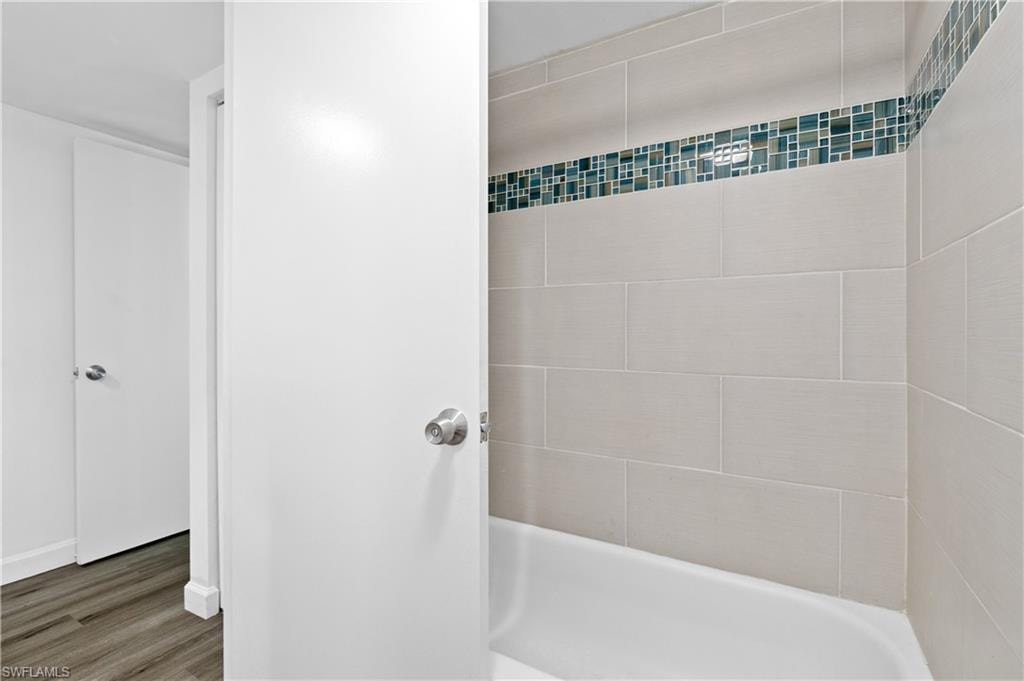 Full bath featuring a shower, a tub, and dark wood-style floors