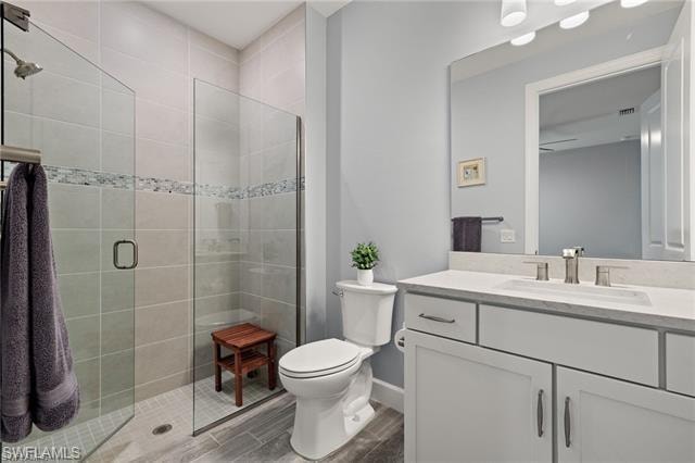 Bathroom featuring vanity, a stall shower, and wood finish floors