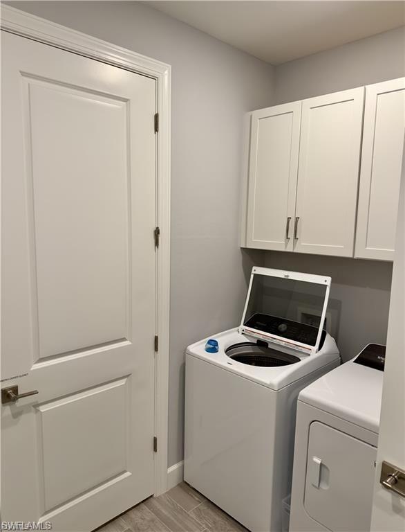 Laundry area with wood tiled floors, cabinet space, and independent washer and dryer