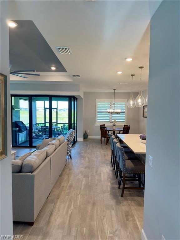 Living area with light wood finished floors, recessed lighting, and a chandelier