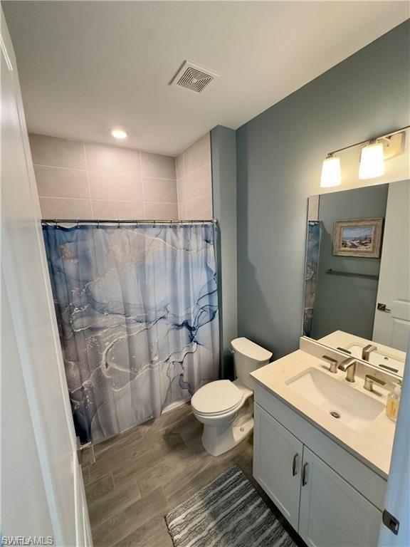 Full bathroom with vanity, a shower with curtain, and wood finish floors