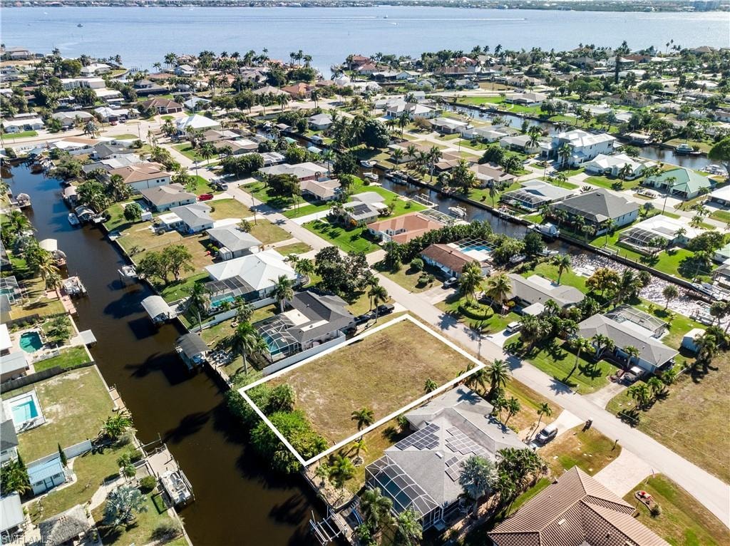 Aerial view of property's location featuring a large body of water, property boundaries highlighted, and nearby suburban area