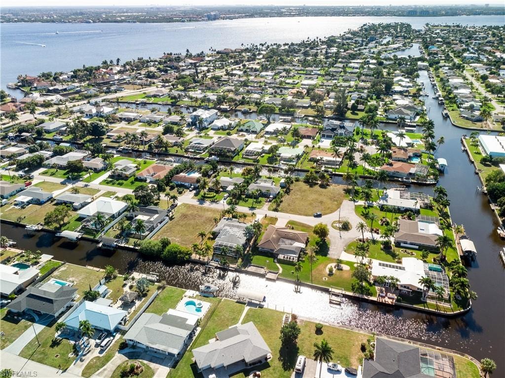 Aerial view of property and surrounding area featuring nearby suburban area and a large body of water