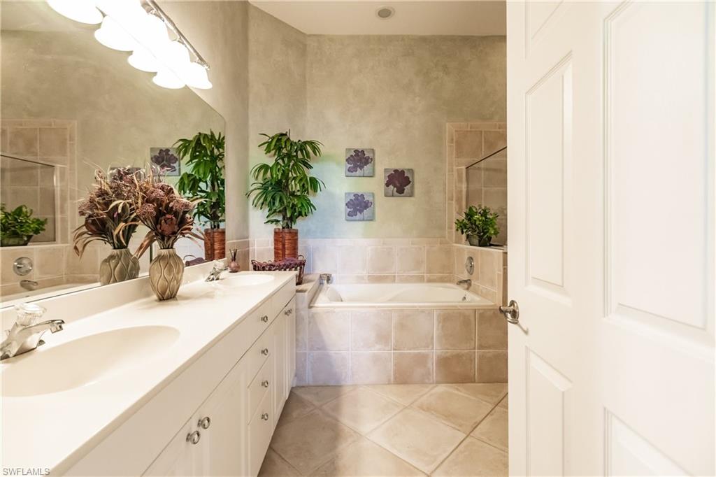 Full bath with a garden tub, double vanity, and light tile patterned flooring
