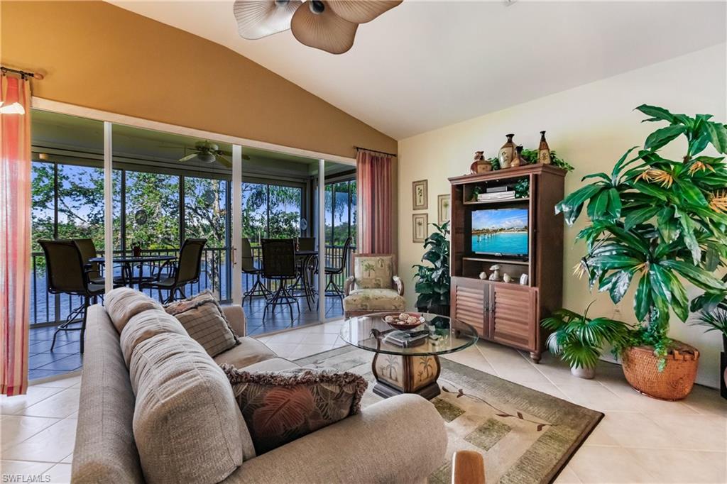 Living area featuring lofted ceiling, tile patterned floors, a sunroom, and a ceiling fan