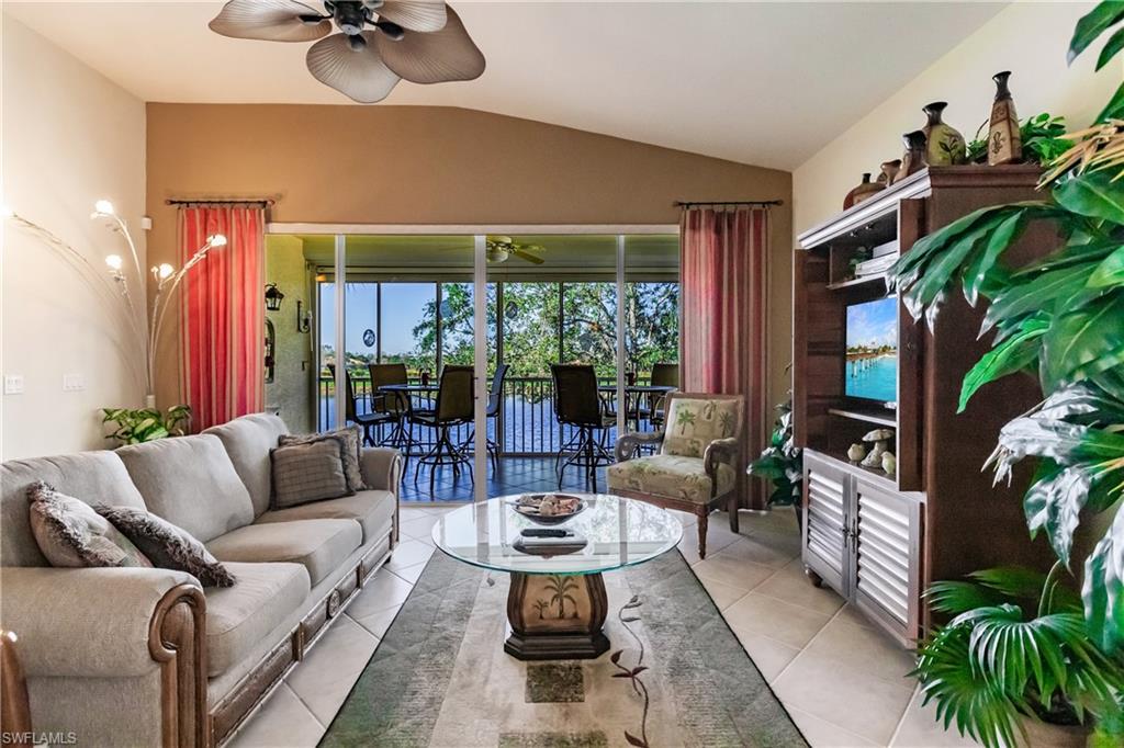 Living room with tile patterned flooring, lofted ceiling, and ceiling fan