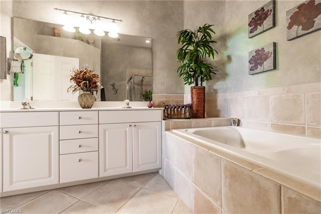 Full bath with double vanity, a bath, light tile patterned flooring, and a shower stall