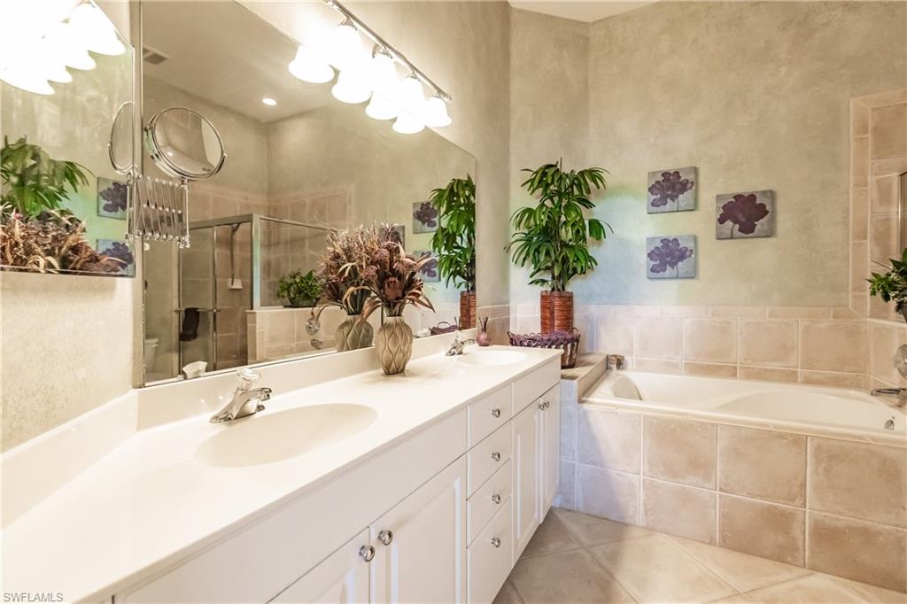 Full bath with a bath, double vanity, a stall shower, and light tile patterned floors