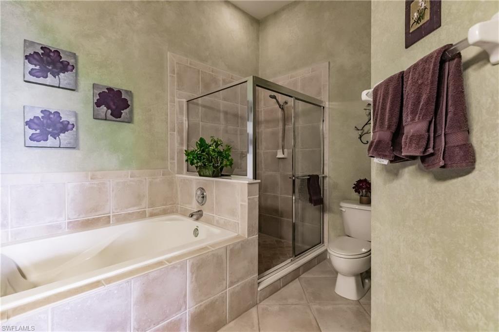 Bathroom featuring a garden tub, a stall shower, light tile patterned flooring, and a textured wall